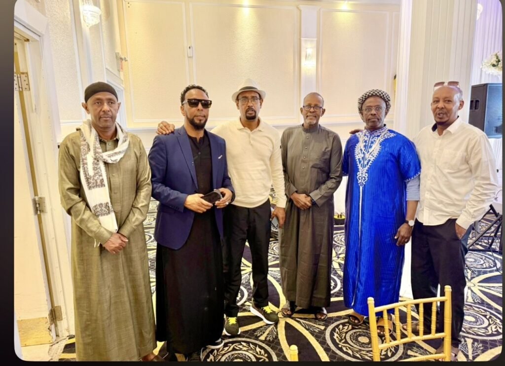 Six community members, several in traditional Somali dress, standing together at a banquet hall gathering