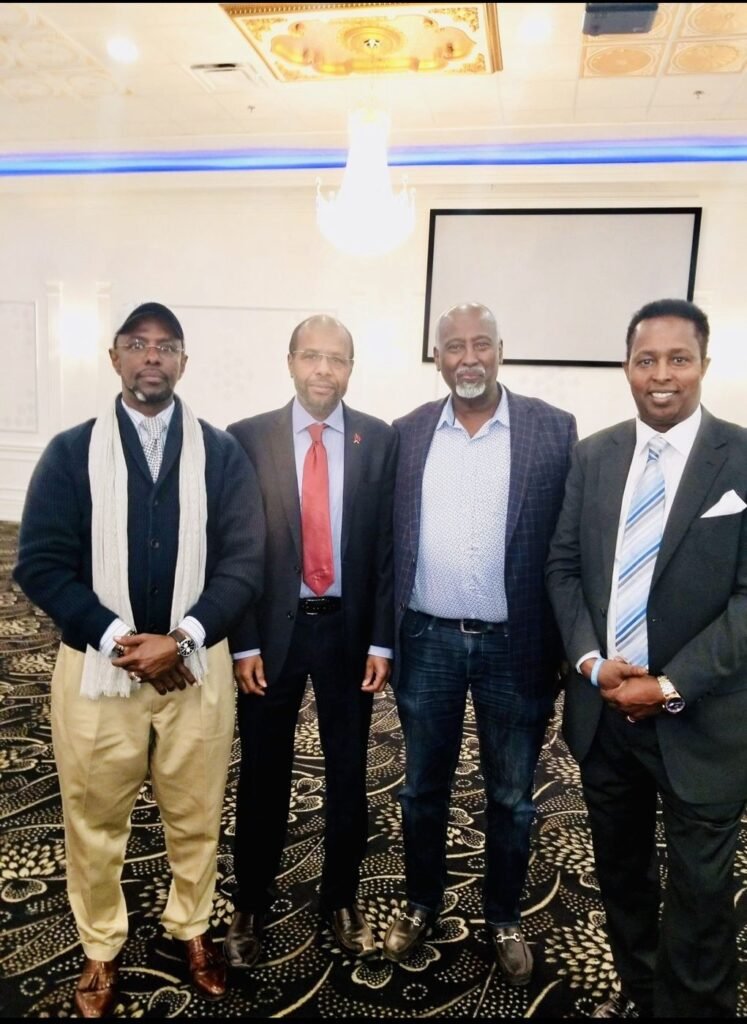 Four community leaders in suits and jackets standing together at a banquet hall event