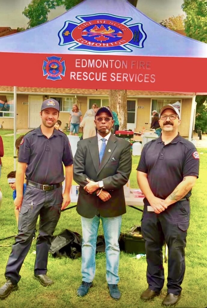 Society leader standing with two Edmonton Fire Rescue Services members at a neighbourhood community event