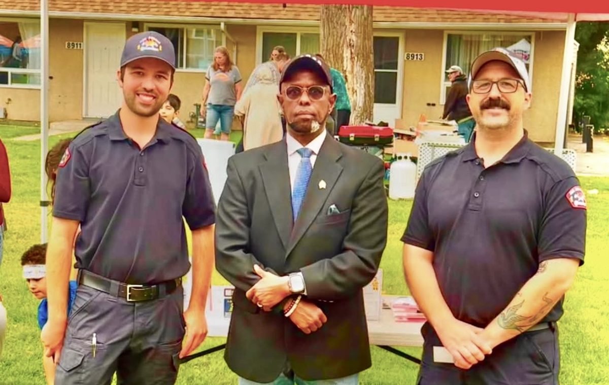 Society leader standing with two Edmonton Fire Rescue Services members at a neighbourhood community event