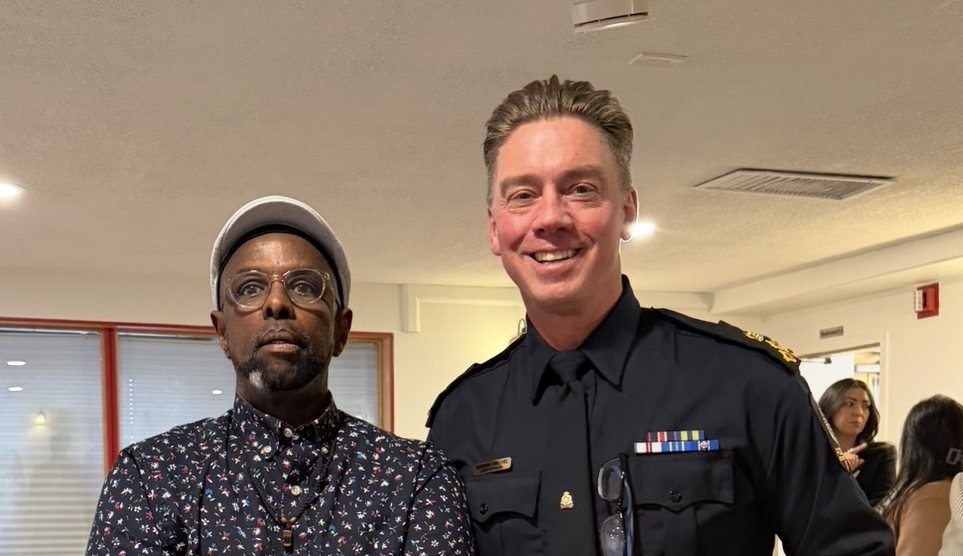 Chairman Ibrahim Shurie standing with a uniformed police officer at a community gathering