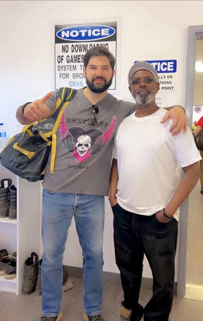 Society leader and a smiling young man giving a thumbs up in a workplace break room