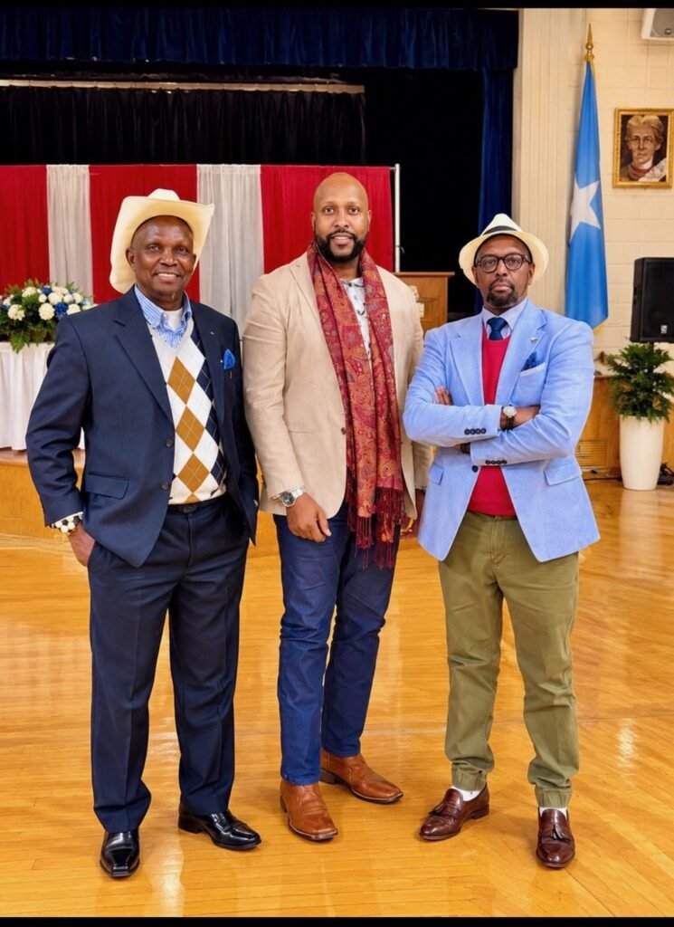 Three community members standing in the hall in front of the Somali flag