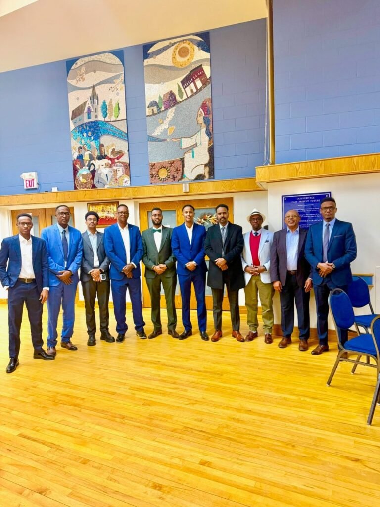 Ten community members, leaders and youth standing in a line in the community hall